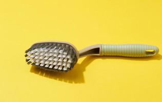 plastic brush with handle for cleaning the house on a yellow background, top view photo