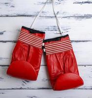 pair of leather worn red boxing gloves hanging on a white lace photo