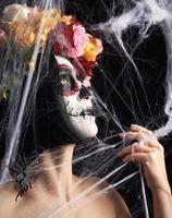 girl with black hair is dressed in a wreath of multi-colored roses and makeup is made on her face Sugar skull photo