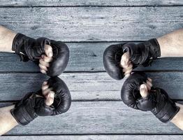 Two pairs of human hands in black leather boxing gloves facing each other photo