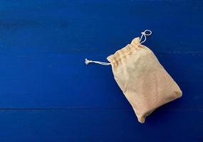 pequeña bolsa de lona completa con lazos, fondo de madera azul foto