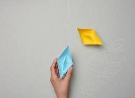 Paper boats with different trajectories on a gray background. The concept of extraordinary thinking photo