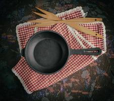 round empty black cast-iron frying pan on a red napkin photo