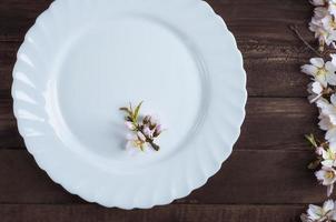 plato blanco vacío con una rama de almendra floreciente foto