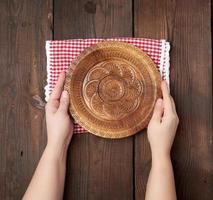two female hands holding an empty round wooden plate photo