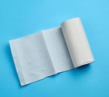 rollo retorcido de toalla de papel blanco sobre un fondo azul. hoja de papel foto