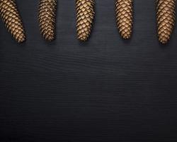 whole brown cones on a black wooden background photo