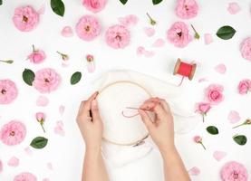 two female hands holding a round wooden hoop and a red thread photo