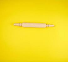 new wooden rolling pin for rolling dough on a yellow background photo