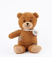 brown teddy bear with rewound white bandage paw on a white background photo