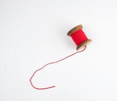 wooden bobbin with red wool threads on a white background photo