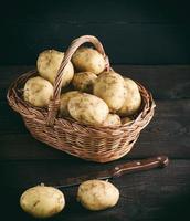 young fresh potatoes in a peel lay in a brown wicker basket photo