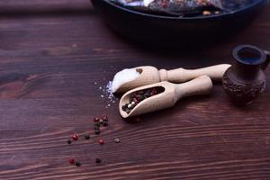 Mixture of black and red pepper in a wooden spoon photo