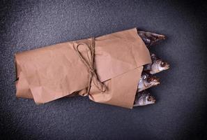withered in salt and dried fish roach wrapped in brown kraft paper photo