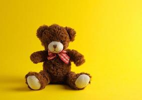 brown teddy bear sitting on a yellow background photo