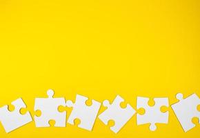 blank white big puzzles on yellow background, flat lay photo