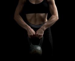 girl of athletic appearance holds an iron kettlebell in front of her photo