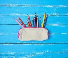 school gray textile pencil case and scattered multicolored wooden pencils photo