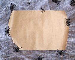 papel marrón sin torcer sobre una telaraña blanca y arañas negras, lugar vacío para escribir foto