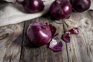 Red onions in the husk on the gray old wooden surface photo