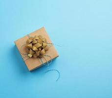 brown square box with a gift tied ribbon with a bow on a blue background, top view photo