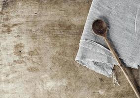 Brown wooden background with a wooden spoon and a gray tablecloth photo