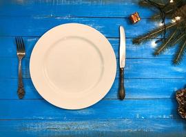 Plate, fork and knife on a blue wooden surface, top view photo