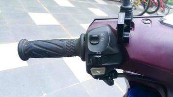 Close up view of horn button, turn signals, and lamp on left motorcycle handlebar. Outdoors. photo