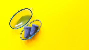 Soft blue foam earplugs in a plastic container on yellow background photo