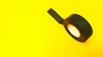 Roll of black sticky duct tape isolated on yellow background photo