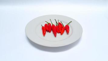 Cerca de chiles verdes rojos en un plato blanco aislado sobre fondo blanco. foto