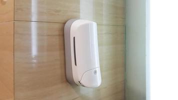 Close up of mounted hand soap dispenser in public toilet or restroom photo
