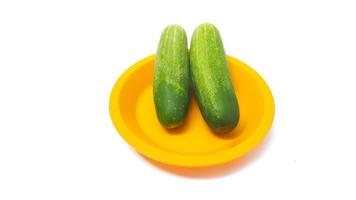 Two cucumbers on a yellow plate isolated white background photo