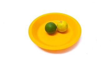 Green limes on a yellow plate isolated on white background. Lime Citrus Fruits. photo