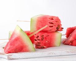 sliced ripe red watermelon with seeds on a wooden white cutting board photo