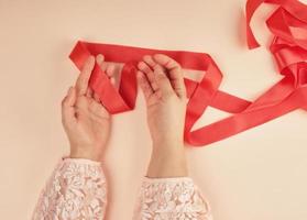 two female hands and red silk ribbon photo