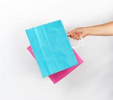 female hand holding four colored paper shopping packaging bags photo