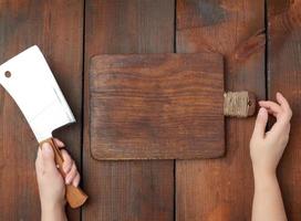 wooden rectangular cutting board and hands hold a large sharp meat knife photo