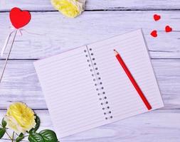 Open blank notebook and red wooden pencil photo