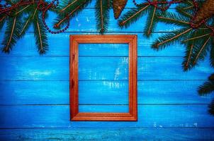 Wooden photo frame on a blue  background with branch fir