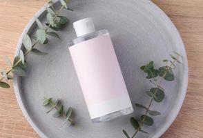 Blank bottle for cosmetics with pink paper label on a gray background. Bottle for tonic photo