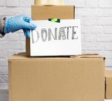 stack of cardboard boxes and white sheet of paper with inscription donate photo