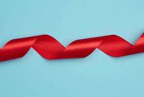 Twisted silk red ribbons for decoration on a blue background, top view photo