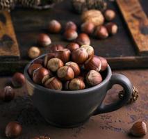 a whole hazelnut nutshell in a brown clay cup photo