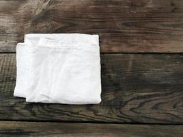 toalla textil de cocina blanca doblada sobre una mesa de madera gris de tablas antiguas foto