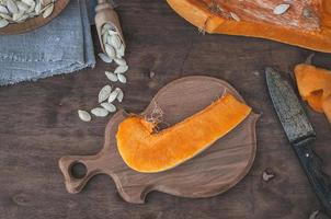 Piece of fresh orange pumpkin on a kitchen cutting board photo