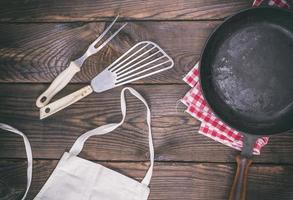 sartén de hierro fundido negro vacío y utensilios de cocina foto