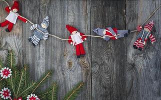 muñeca de trapo navidad colgando de la cuerda en la superficie de madera vieja gris foto