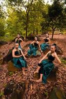 un grupo de bailarines indonesios sentados maravillosamente en la roca con hojas marrones en el fondo dentro del bosque foto