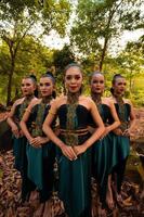 Glamor Asian women with green costumes and makeup line up together in the jungle with brown leaves on the ground photo